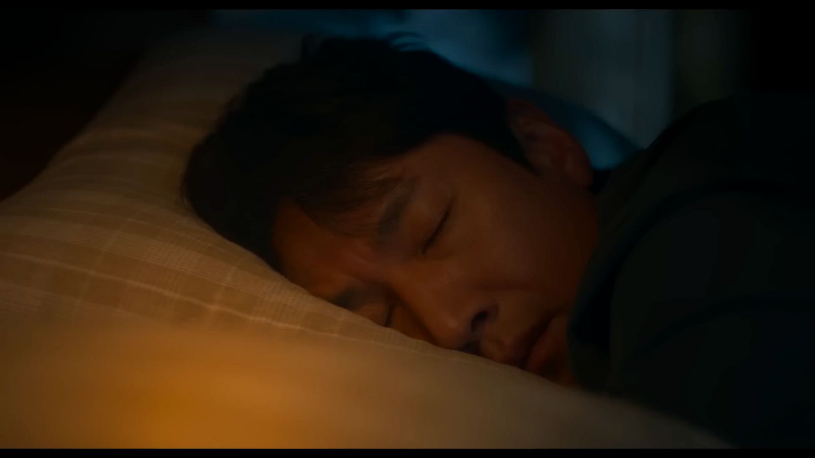 a young boy sleeping on a bed with his eyes closed