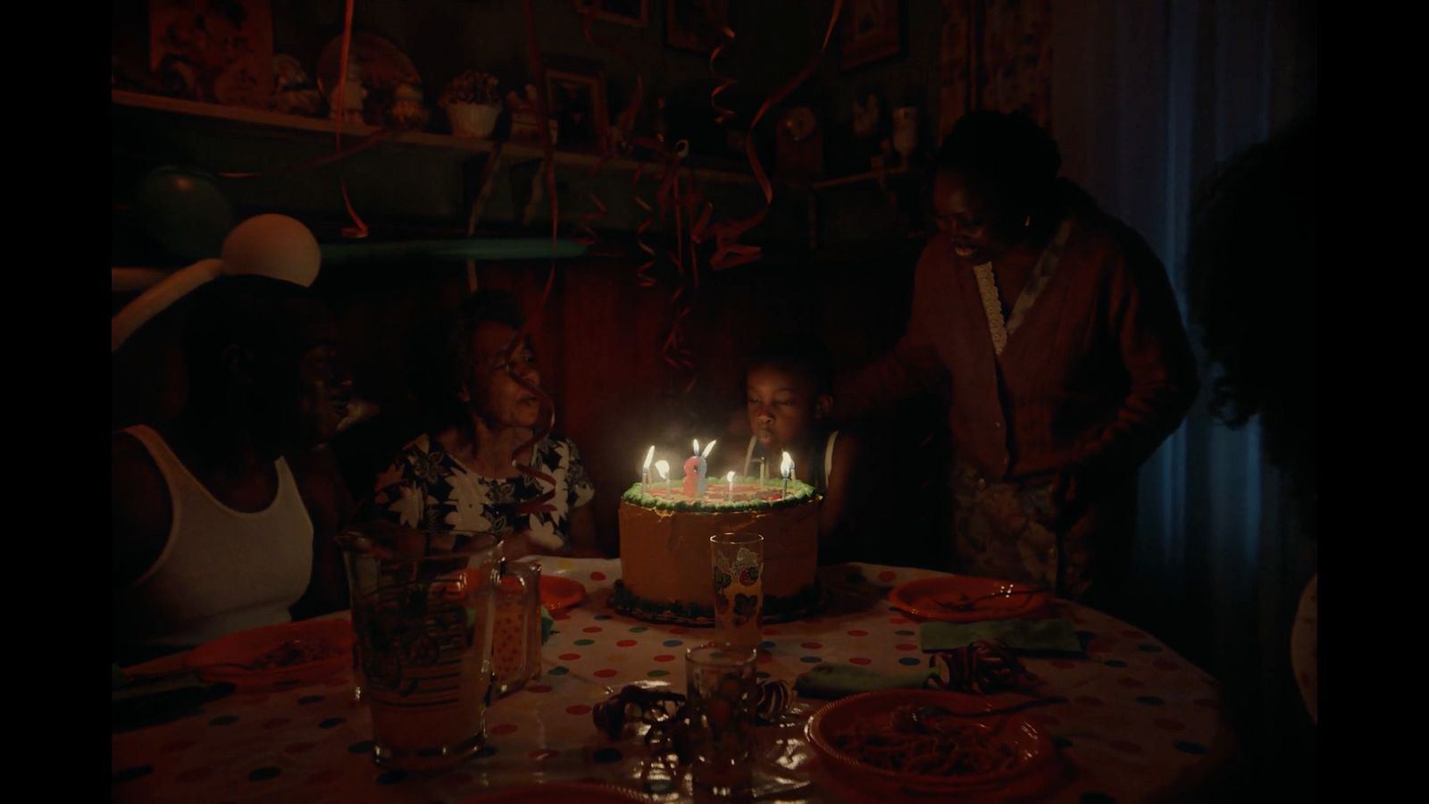 a group of people standing around a table with a cake