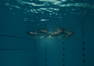 a person swimming in a pool with a surfboard