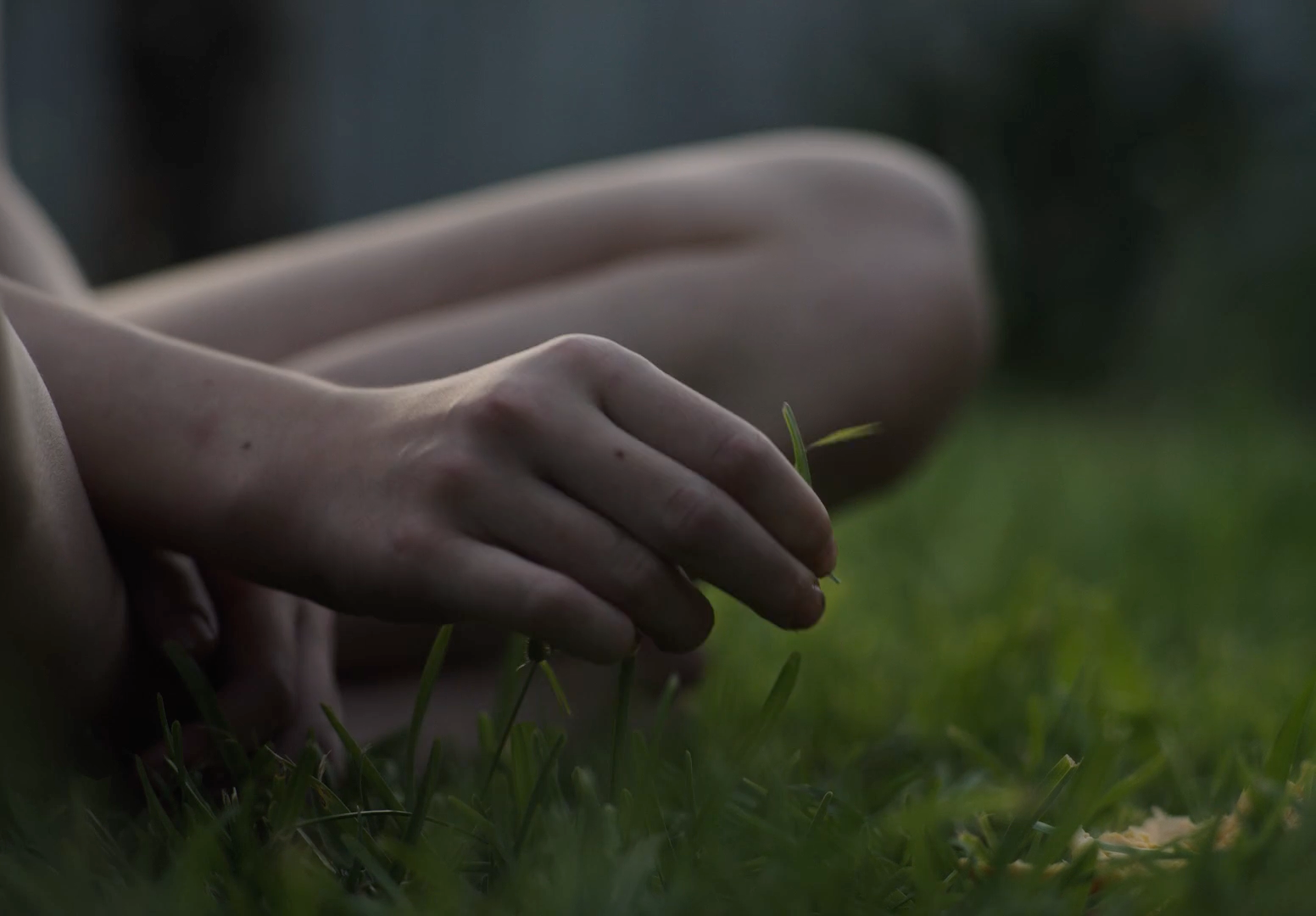 a person sitting in the grass with their hands on the ground