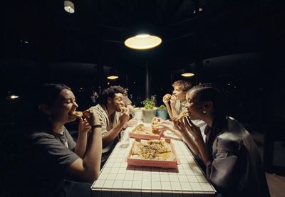 a group of people sitting around a table eating pizza