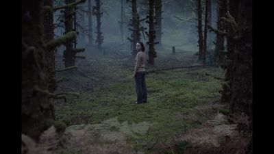 a woman standing in the middle of a forest