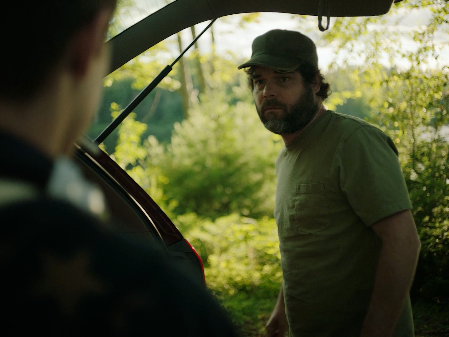 a man standing next to a car in a forest