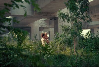 a woman standing in the middle of a lush green forest