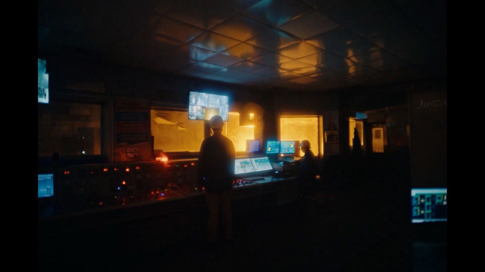 a man standing in front of a computer monitor in a dark room