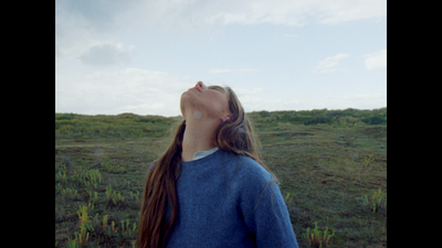 a woman standing in a field looking up into the sky