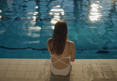 a woman sitting on the edge of a swimming pool