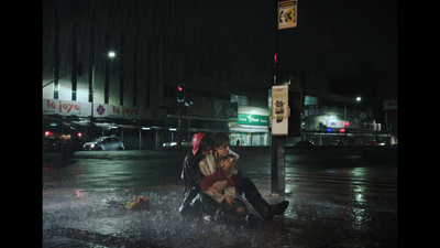 a man and a woman sitting on a curb in the rain