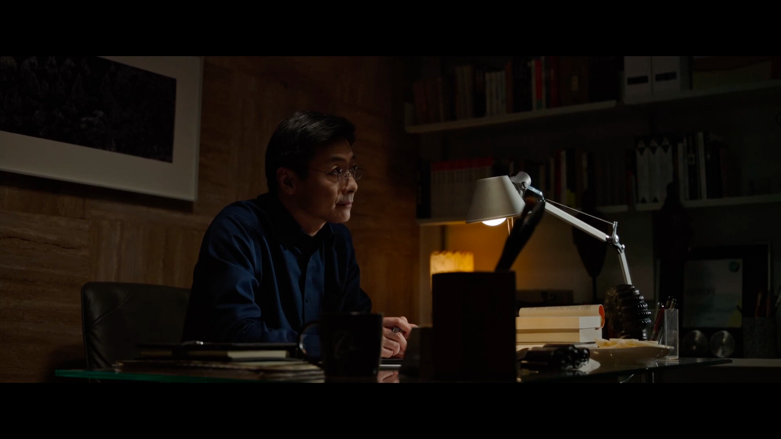 a man sitting at a desk in front of a lamp