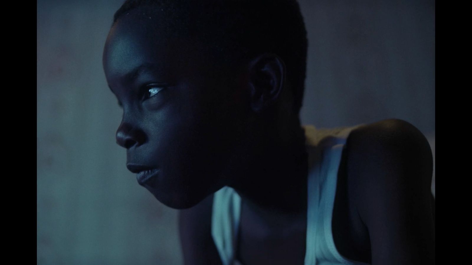 a young boy in a tank top stares at the camera