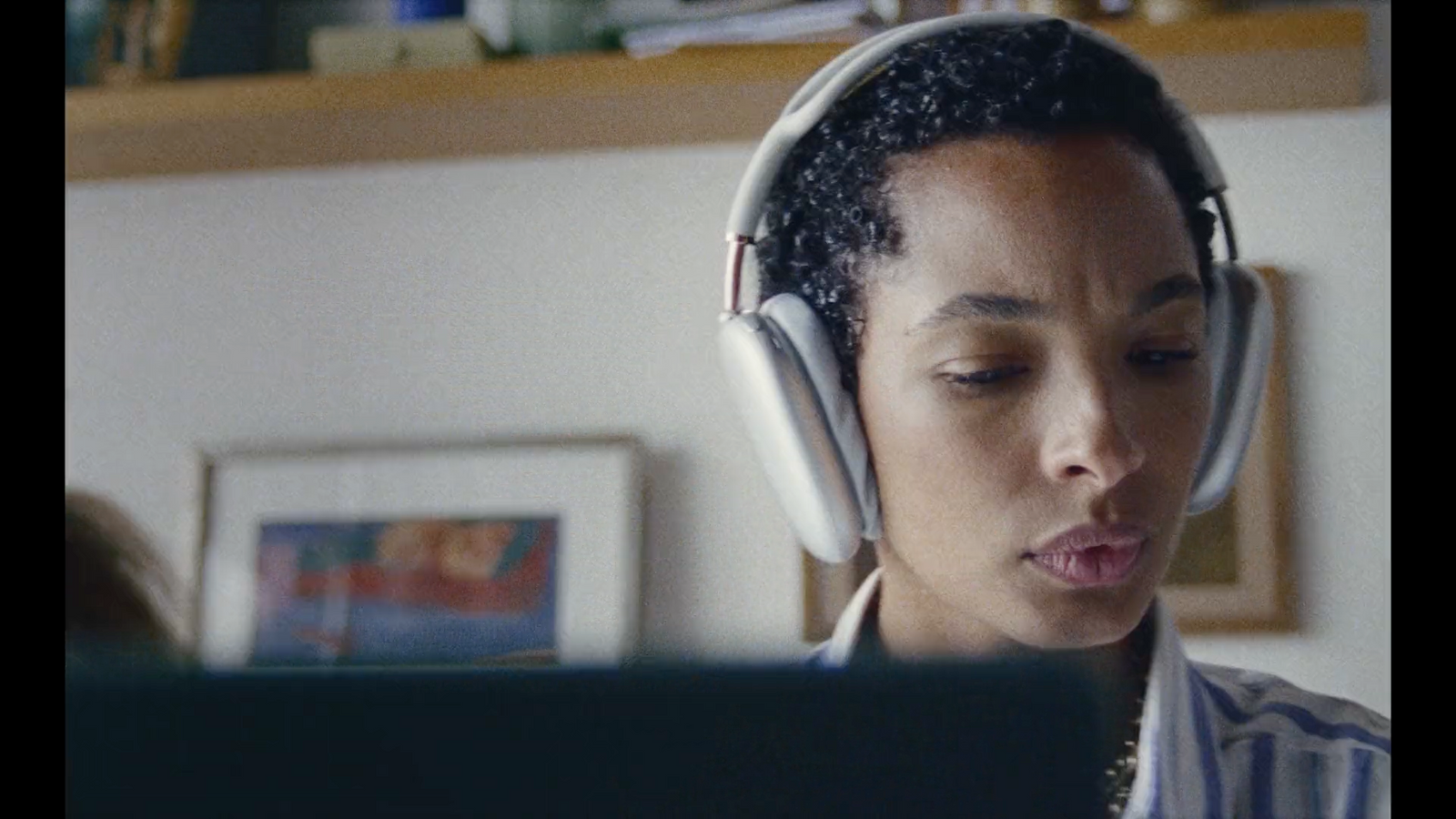 a woman wearing headphones looking at a laptop