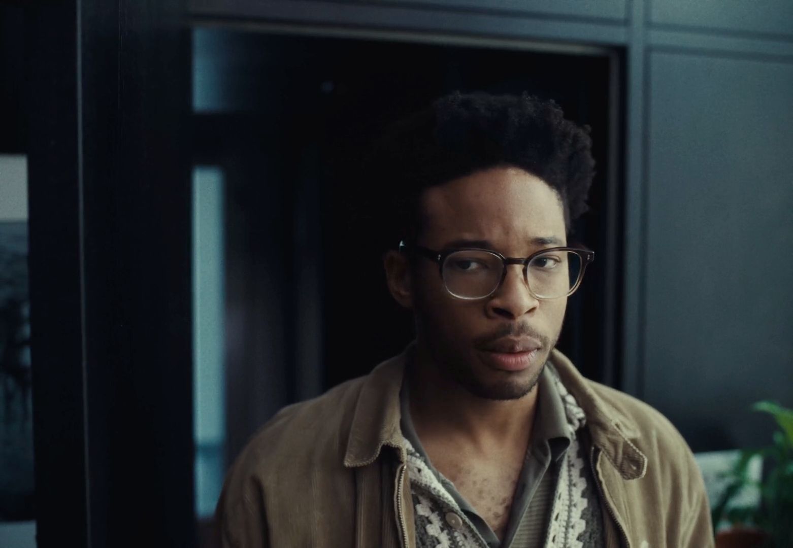 a man with glasses standing in a room