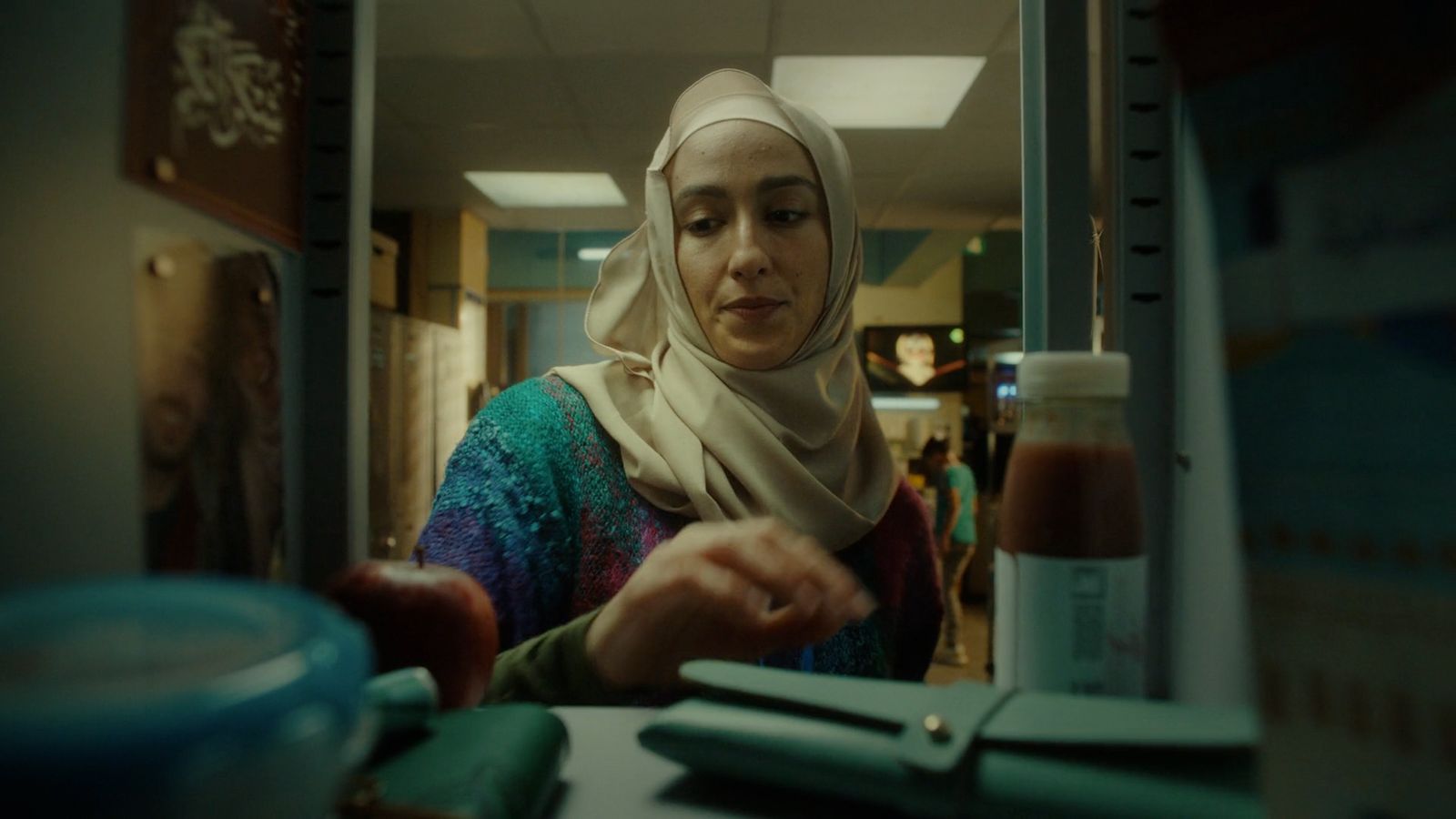 a woman in a headscarf is looking at a bottle