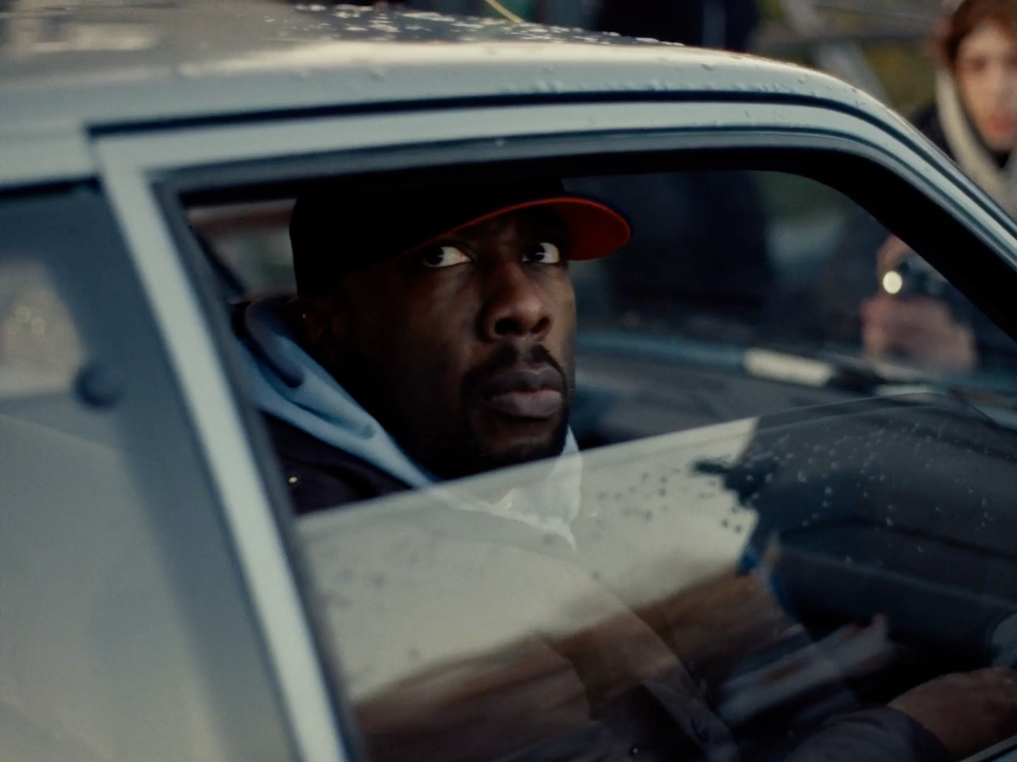 a man sitting in a car with a woman behind him