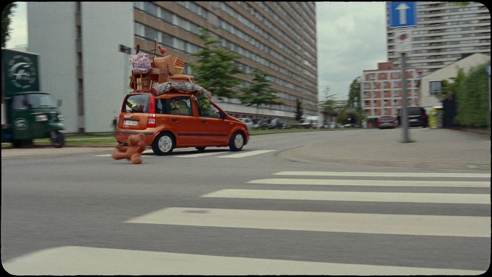 an orange car driving down a street next to tall buildings