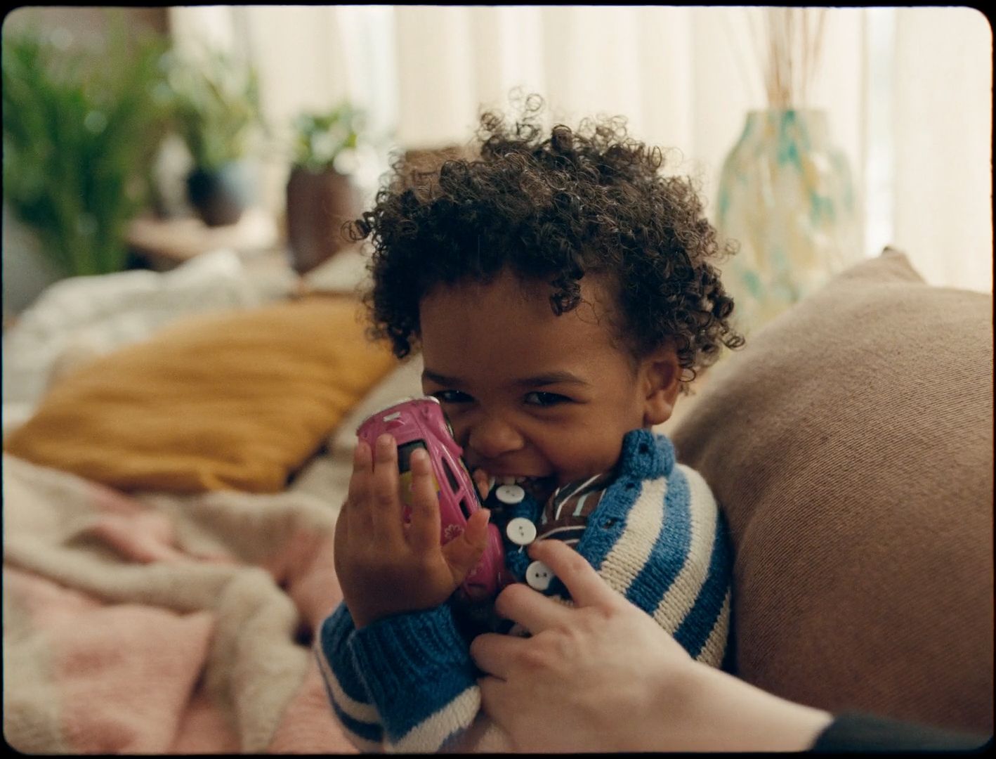 a little girl sitting on a couch holding a cell phone