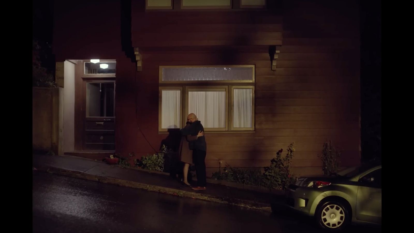 a man and woman standing outside of a house at night