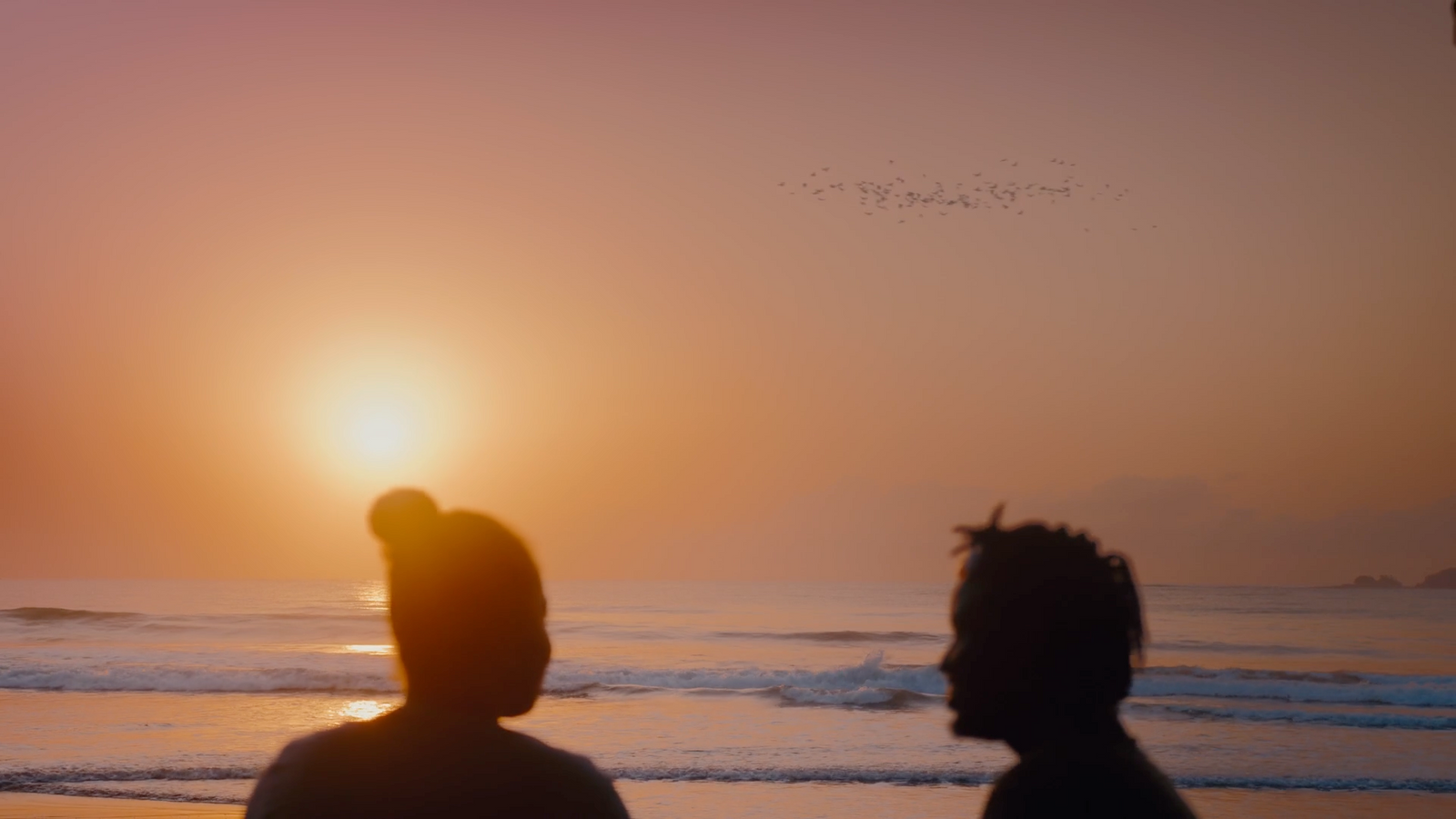 a couple of people standing on top of a beach