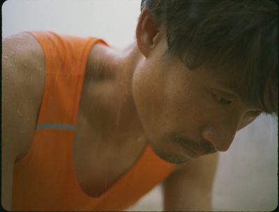 a man in an orange tank top looking down