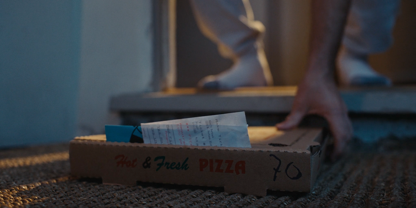 a box of pizza sitting on the floor next to a person