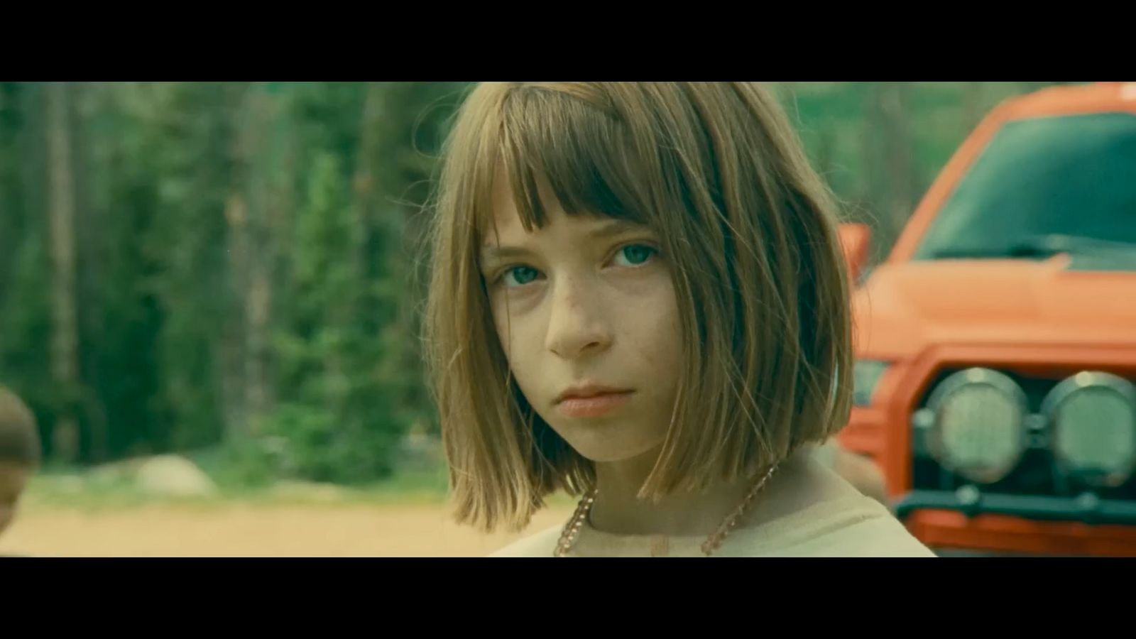 a young girl standing in front of a red truck