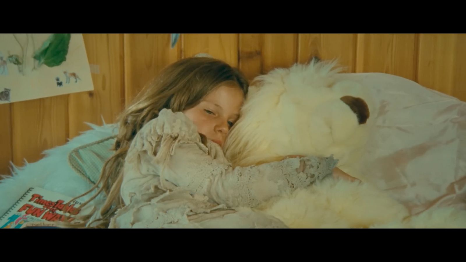 a little girl laying in bed with a stuffed animal