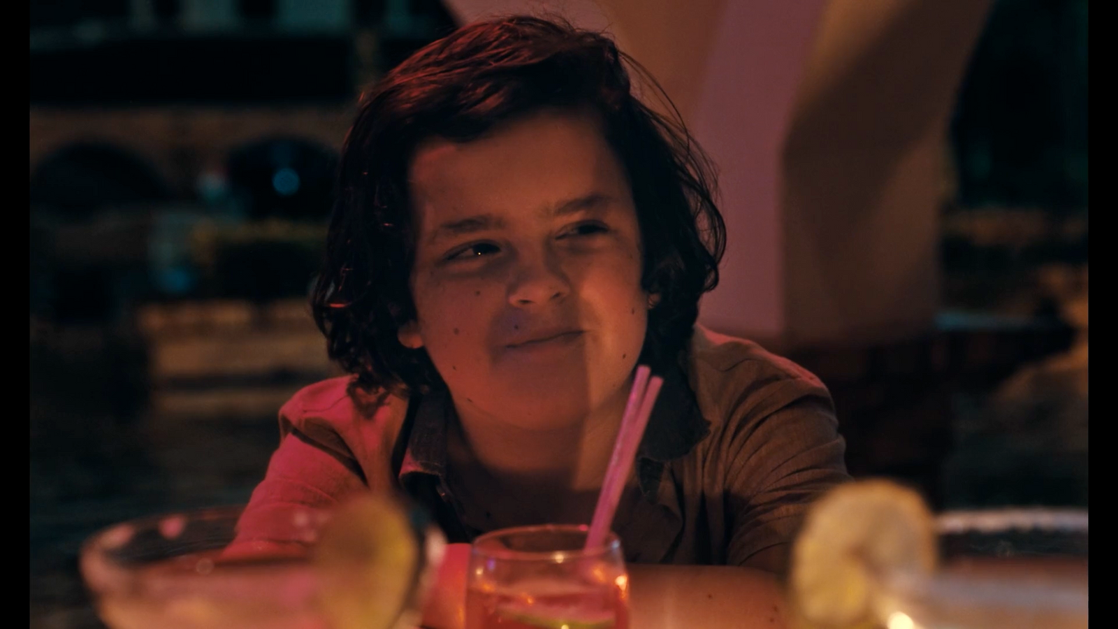 a woman sitting at a table with a drink in front of her