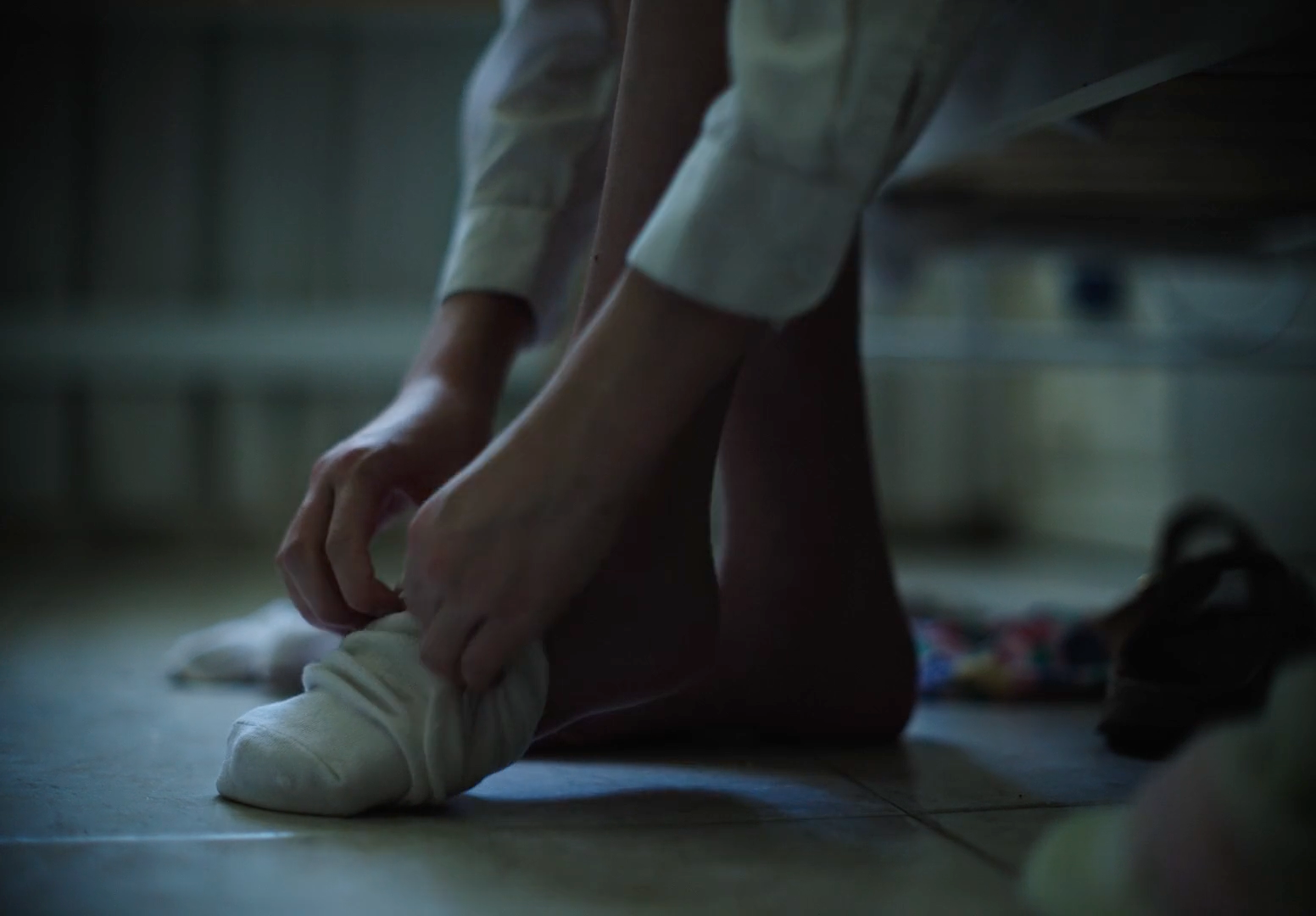 a person tying a pair of shoes on the floor