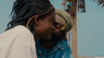 a woman with dreadlocks kissing a man on the beach