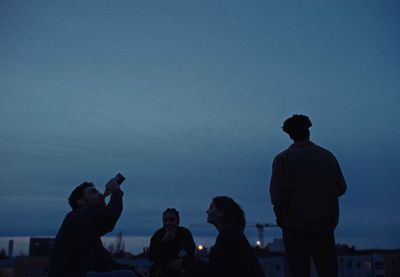 a group of people sitting on a roof at night