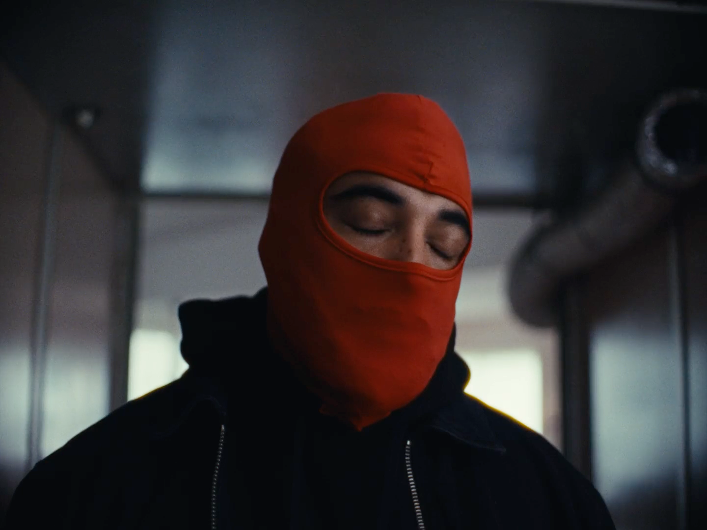 a man wearing a red mask and a black jacket