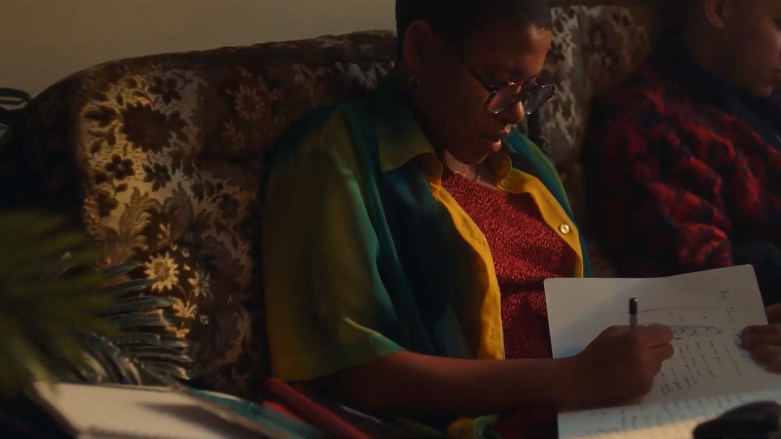 a woman sitting on a couch writing on a piece of paper