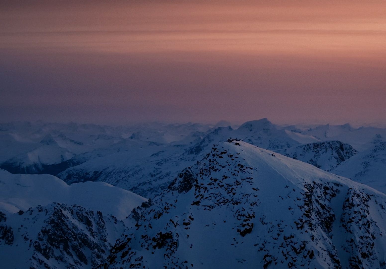 a view of a snowy mountain range at sunset