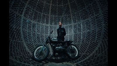 a man standing next to a motorcycle in a cage