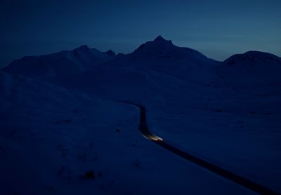 a car driving down a snow covered road at night