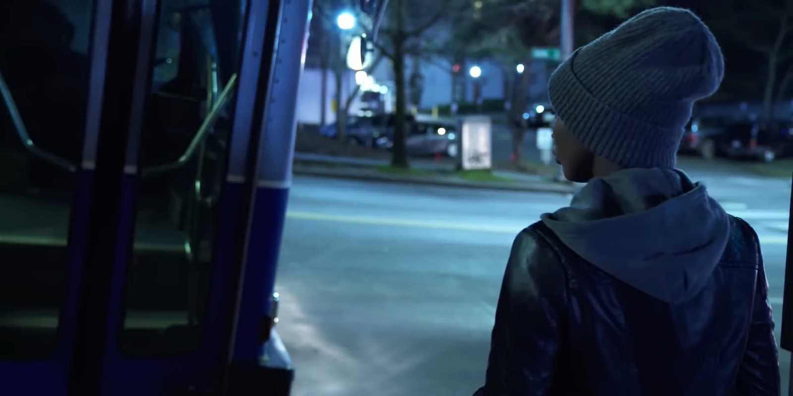 a person in a beanie standing at a bus stop