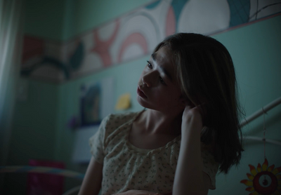 a woman sitting in a room with her hand on her head