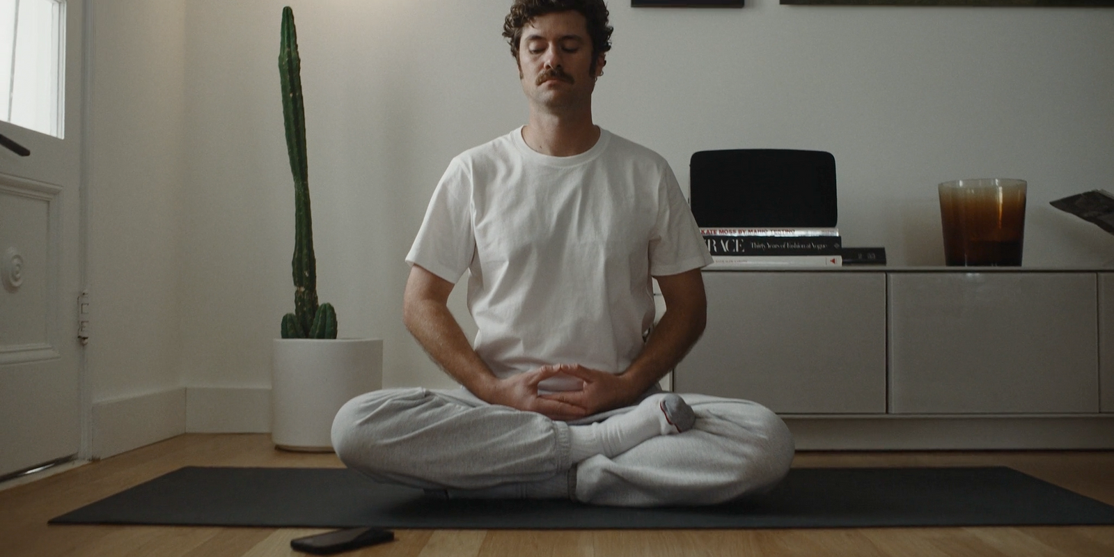 a man sitting on a yoga mat in the middle of a room