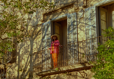 a woman standing on a balcony next to a tree