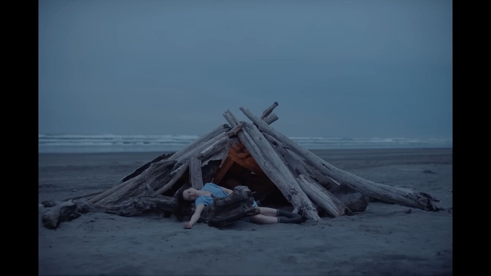 a person laying down in front of a pile of logs