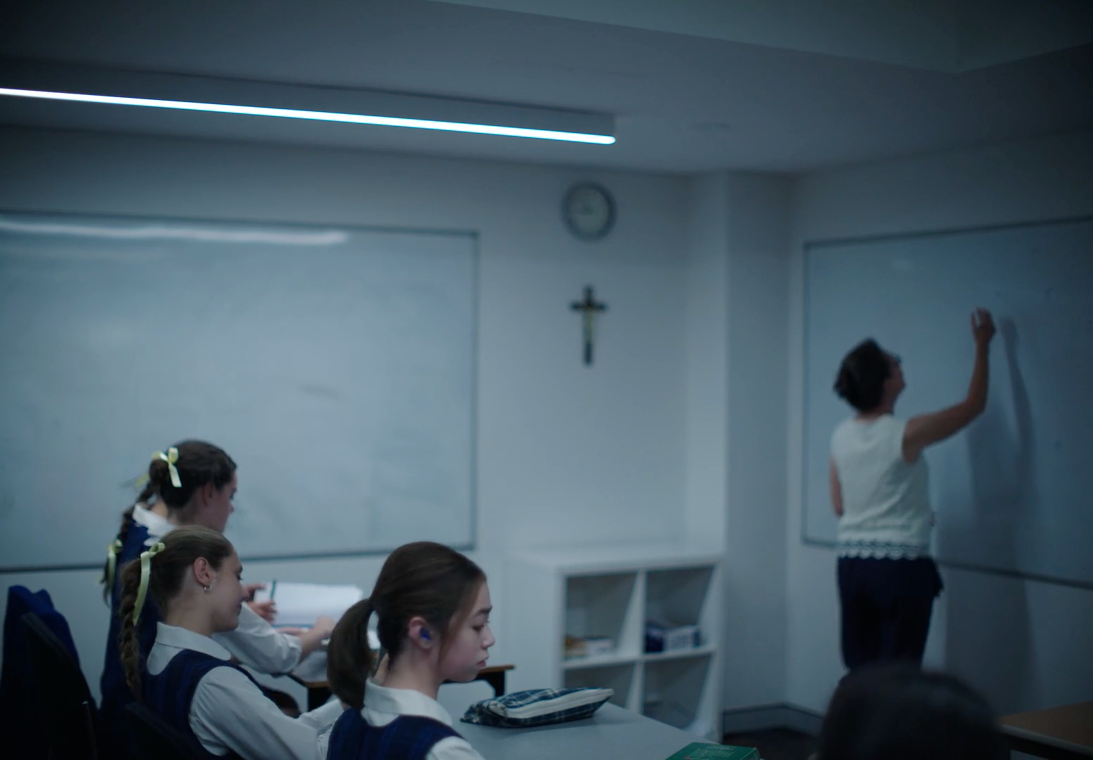 a group of girls sitting at a table in front of a whiteboard