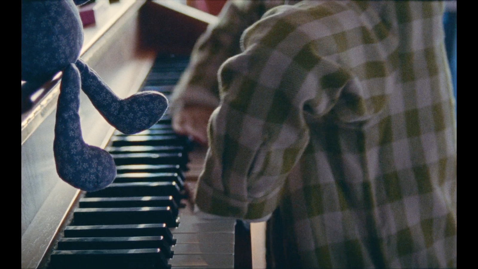 a person playing a piano with a stuffed animal