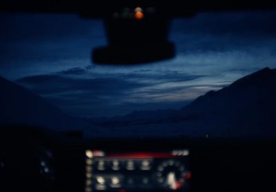 a car dashboard with a view of a mountain range at night