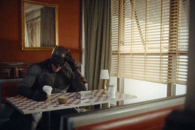 a man in a batman costume sitting at a table