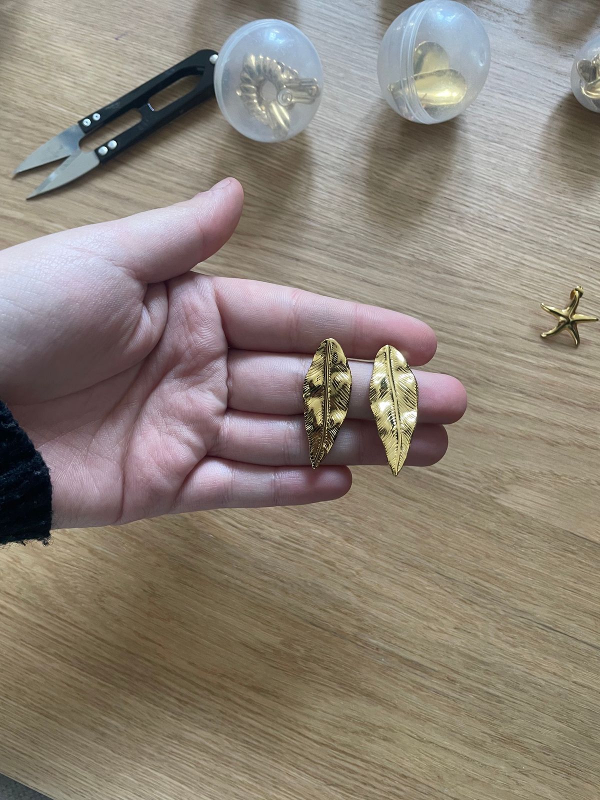 a person is holding a pair of earrings
