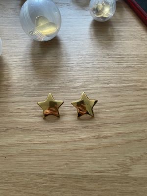 a pair of gold star earrings sitting on top of a wooden table