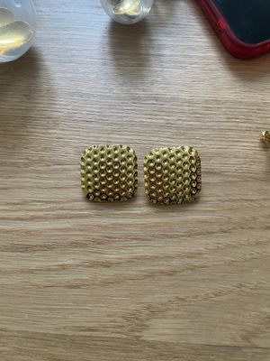 a pair of gold earrings sitting on top of a wooden table