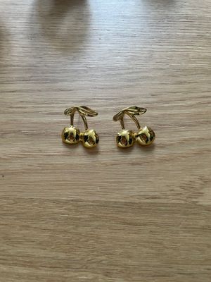 a pair of gold toned cufflinks on a wooden table