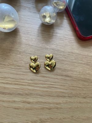 a pair of heart shaped earrings sitting on top of a wooden table