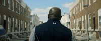 a man walking down a street next to tall buildings